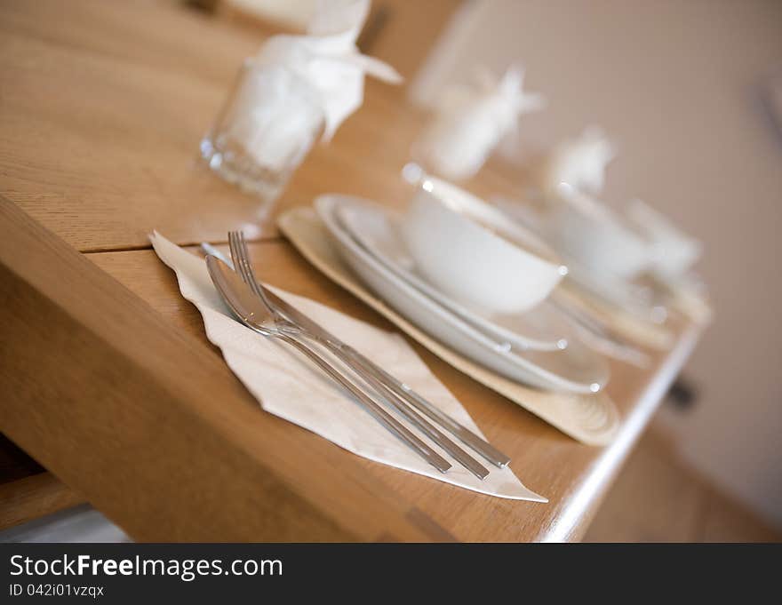 White crockery breakfast place setting on a wooden kitchen table angled shot