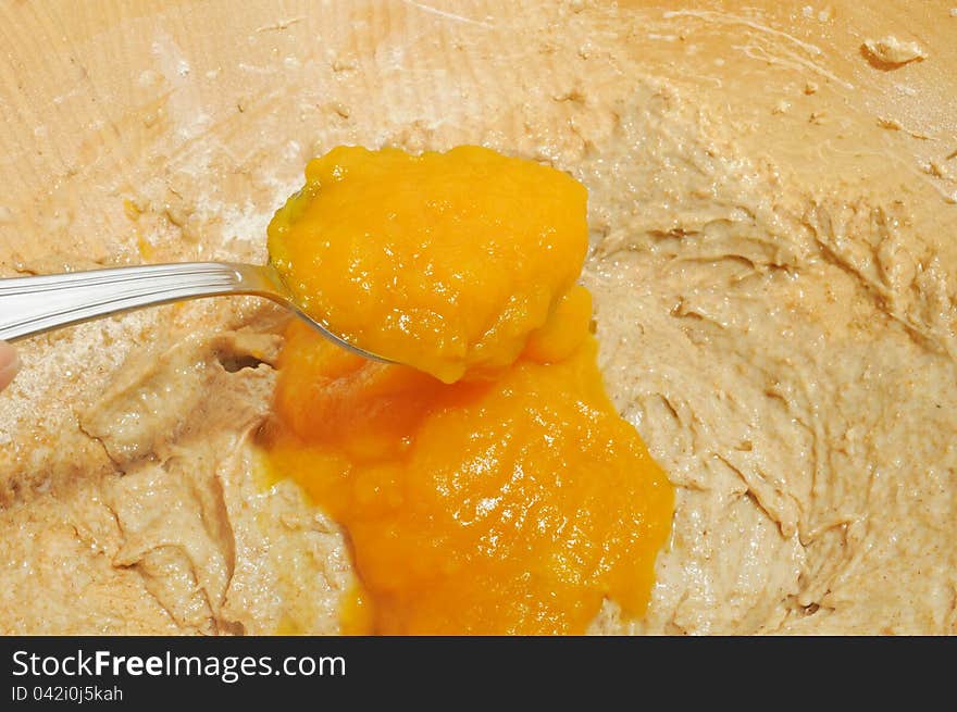 Pumpkin puree being added into a bowl with dough for a pumpkin pie. Pumpkin puree being added into a bowl with dough for a pumpkin pie