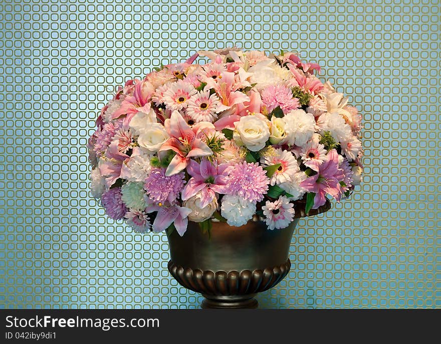 Bouquet of flowers in a brass vase, textured walls in the background