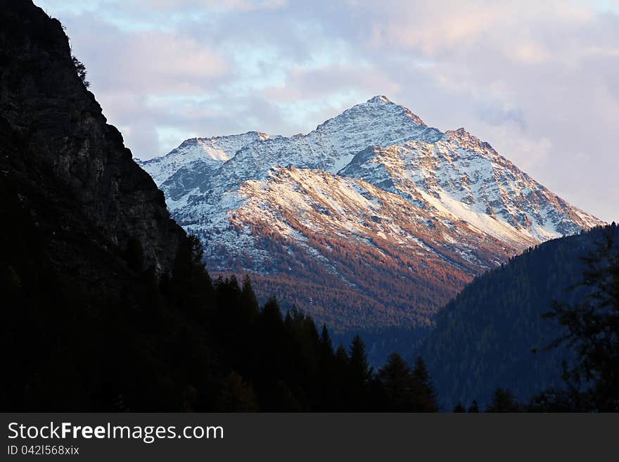 Snowy mountain peak is softly touched by last sunset light. Snowy mountain peak is softly touched by last sunset light