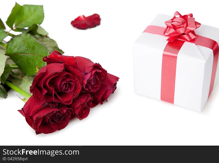 A bouquet of roses and gift box with red ribbon on white background. A bouquet of roses and gift box with red ribbon on white background.