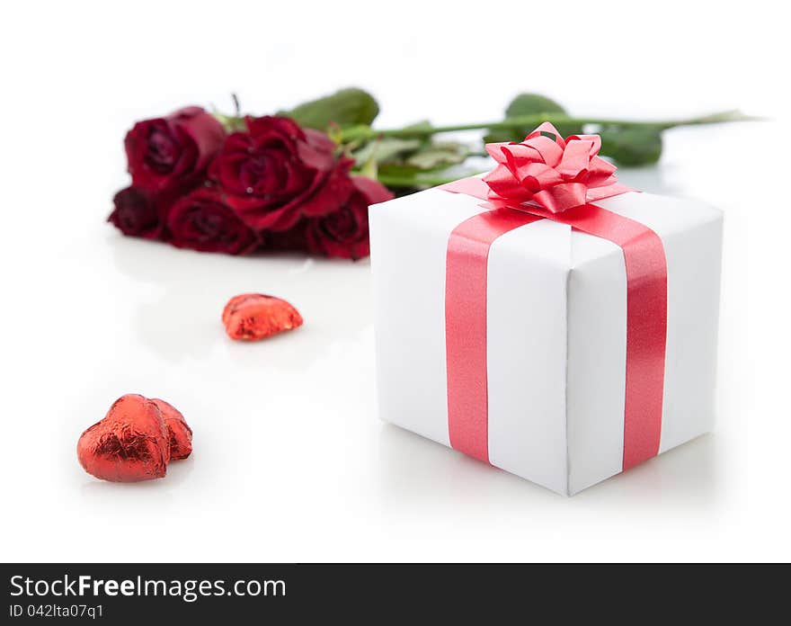 A bouquet of roses and gift on white background.