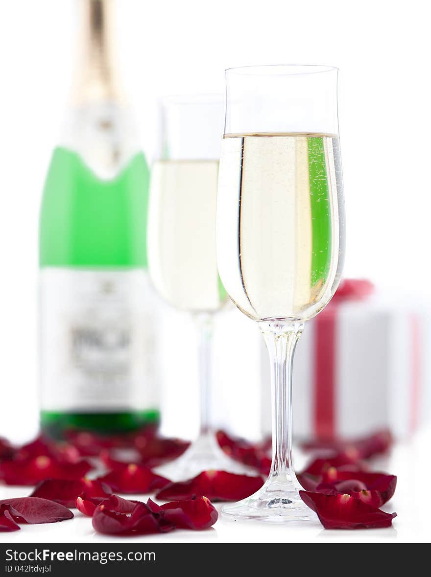 Two glasses of champagne, gift box, rose petals on white background. Two glasses of champagne, gift box, rose petals on white background.