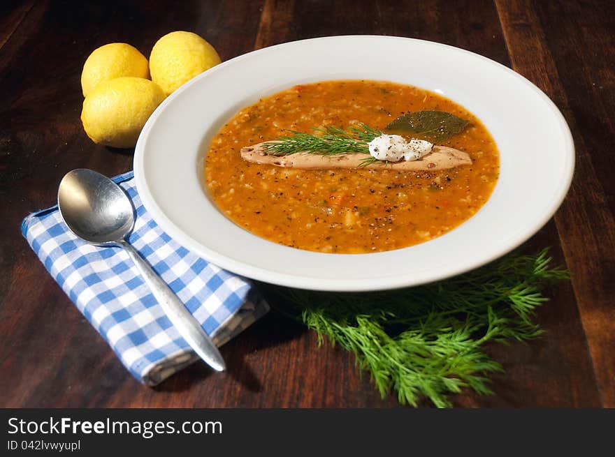 Overhead view of bowl of tomato soup with garnish on oak table. sharp at the soup. Overhead view of bowl of tomato soup with garnish on oak table. sharp at the soup