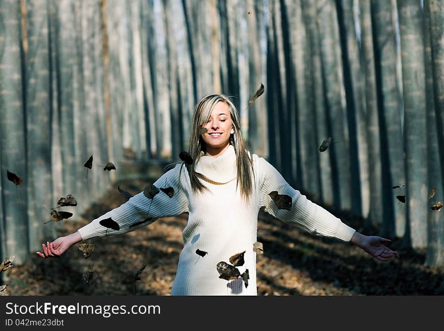 Beautiful blonde girl with falling leaves in the autumn park