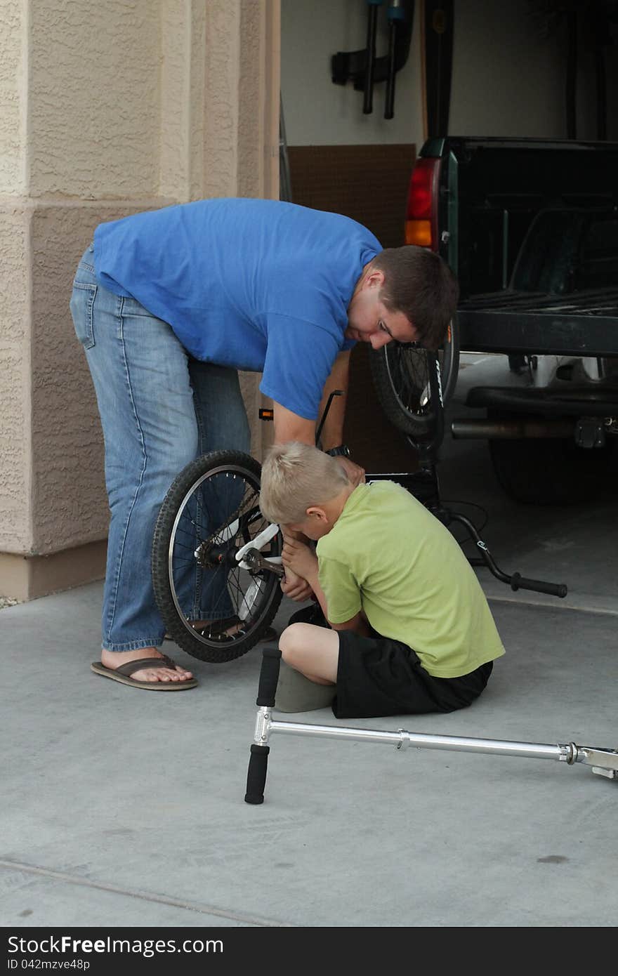 A boy and his dad fix a bike. A boy and his dad fix a bike