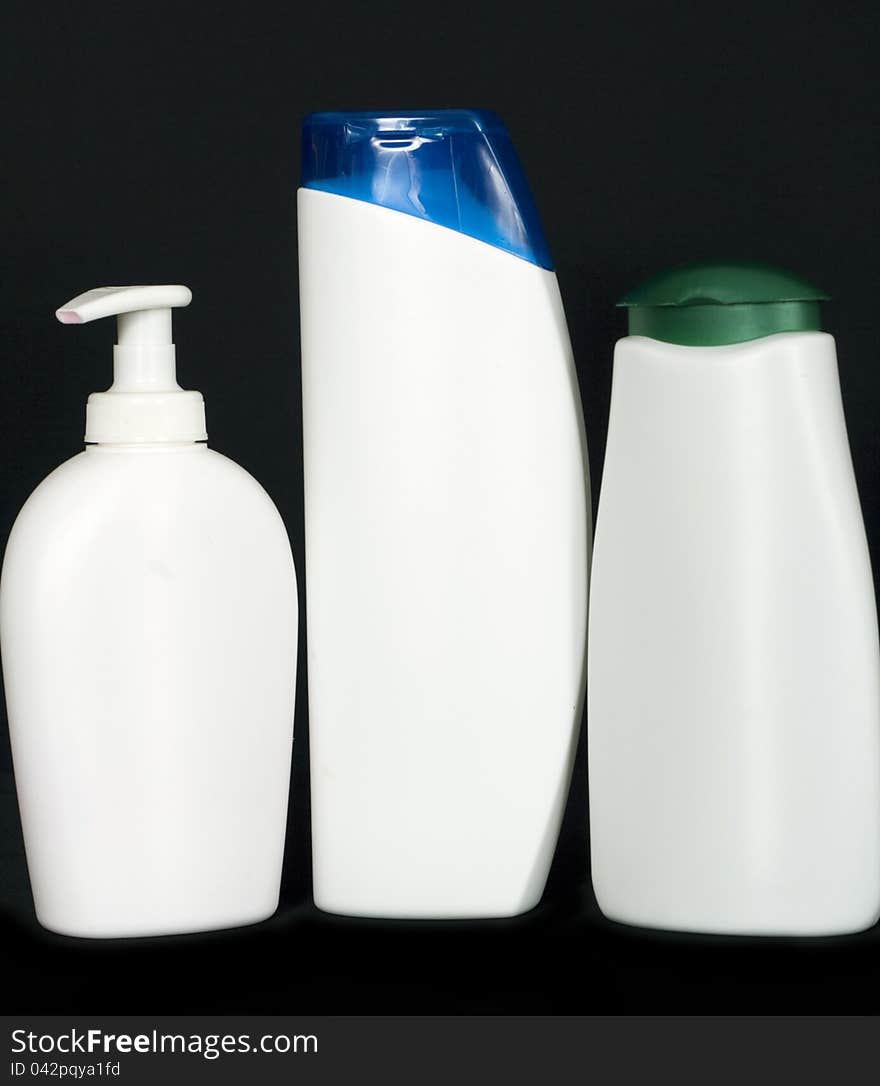 Three white plastic bottles arranged in a row on black background