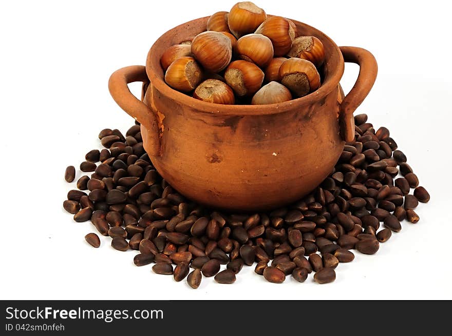 Pot with hazelnuts, pine nuts surrounded, , close-up. Pot with hazelnuts, pine nuts surrounded, , close-up