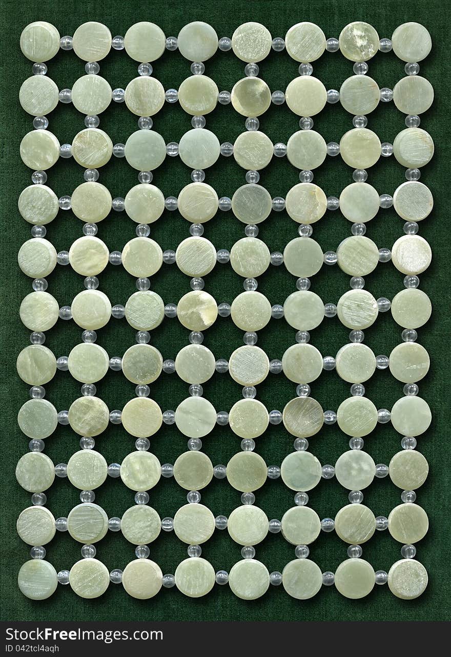 Grid of nephrite discs on green velvet. High resolution texture.