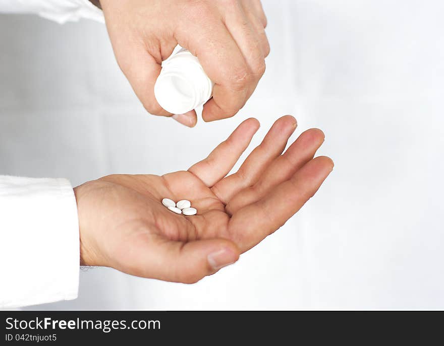 Male hand holding pills in one hand and an empty bottle in the other hand, selective focus, with space for text.