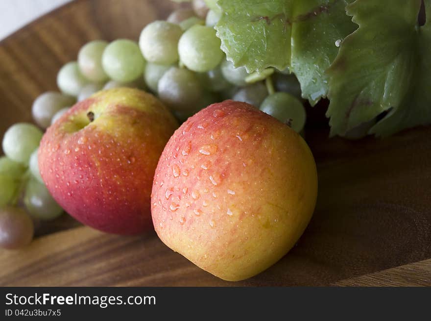 Close up fresh apples with grapes on wooden tray