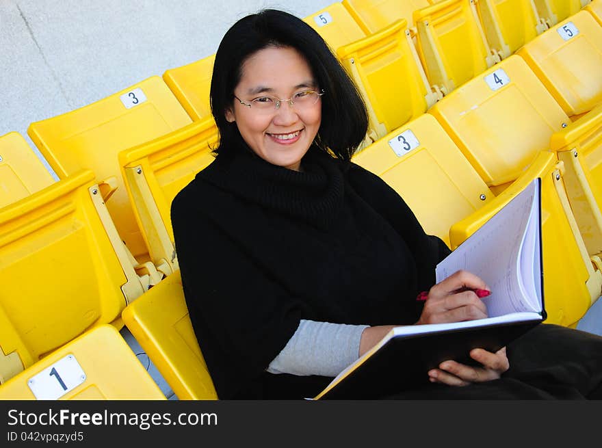 Young Asian college student with smiling sitting on grandstand to present education concept. Young Asian college student with smiling sitting on grandstand to present education concept