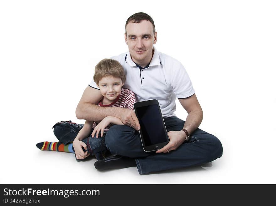 Father and son sitting on a floor with the computer on white isolation. Father and son sitting on a floor with the computer on white isolation