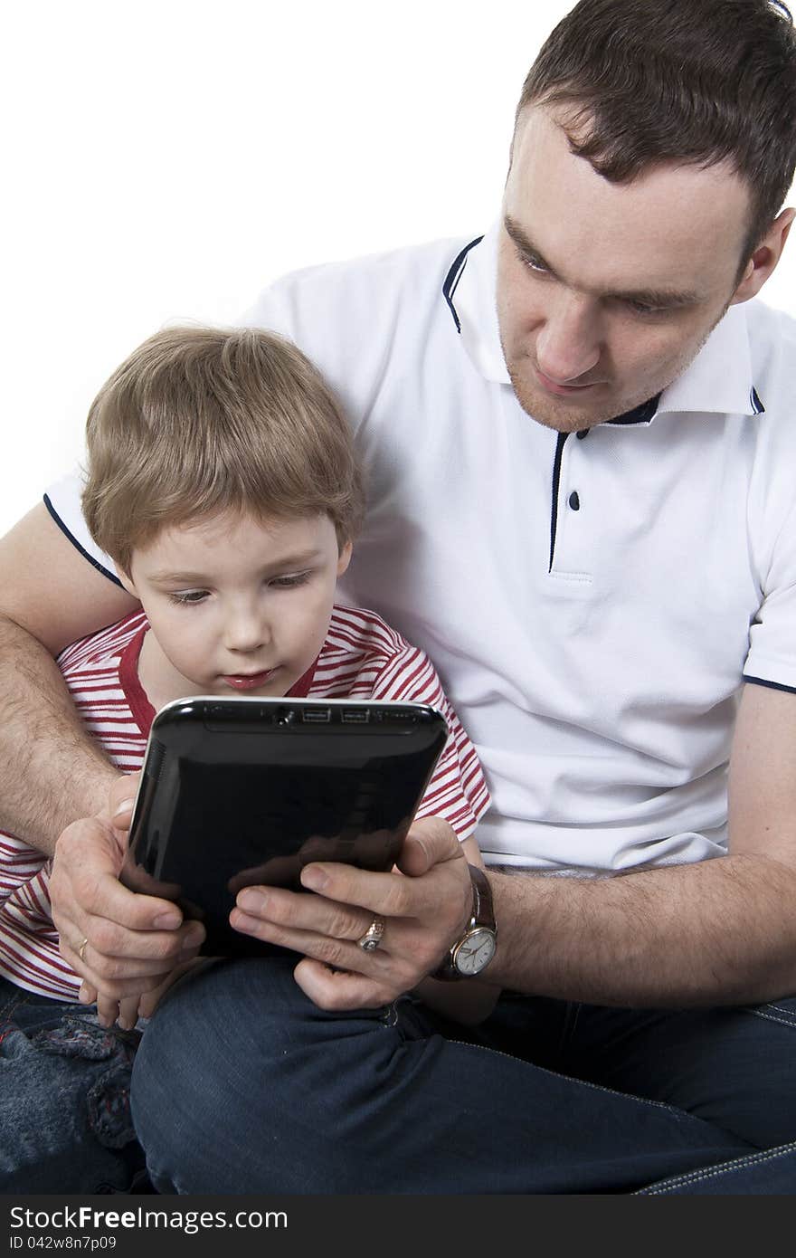 Father and son sitting on a floor with the computer on white isolation. Father and son sitting on a floor with the computer on white isolation