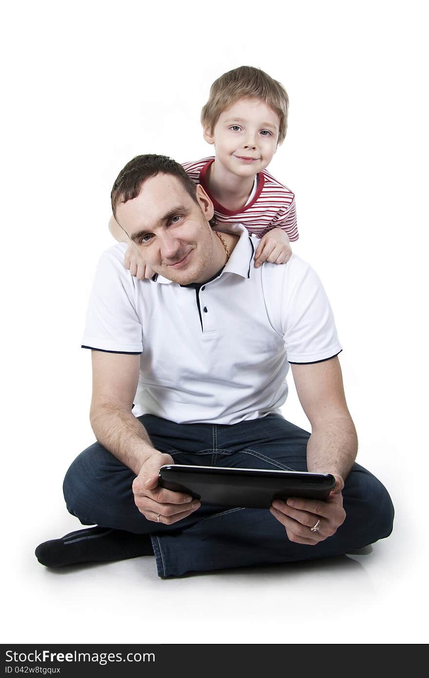 Father and son sitting on a floor with the computer on white isolation. Father and son sitting on a floor with the computer on white isolation