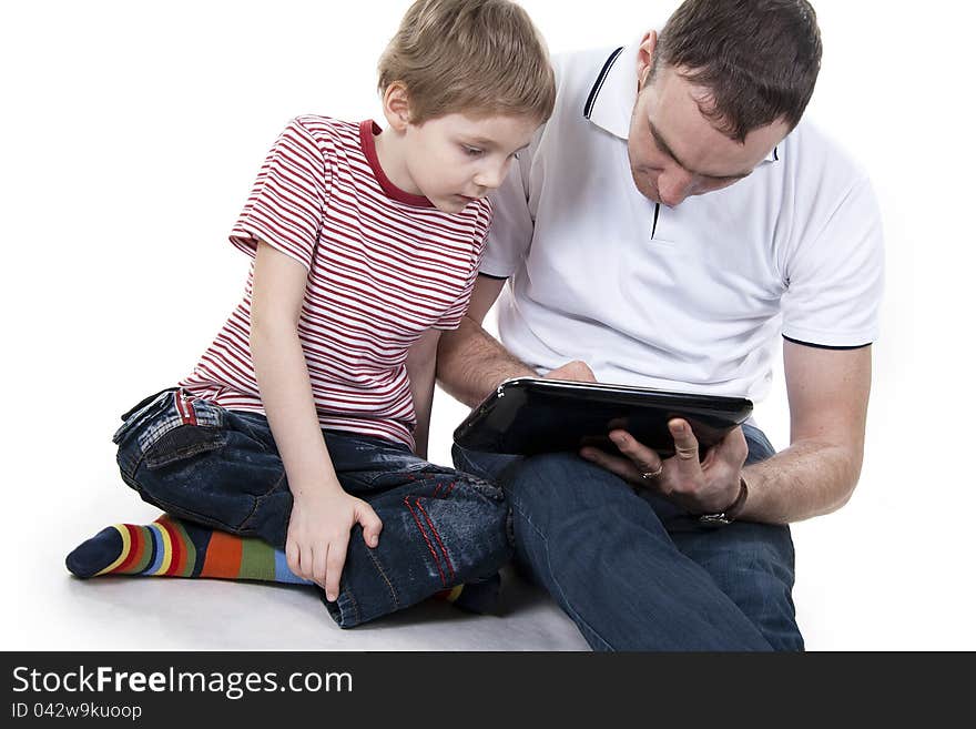 Father and son sitting on a floor with the computer on white isolation. Father and son sitting on a floor with the computer on white isolation