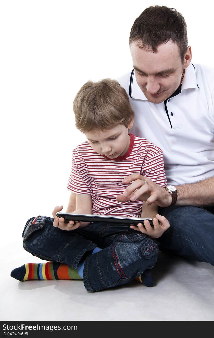 Father and son sitting on a floor with the computer on white isolation. Father and son sitting on a floor with the computer on white isolation