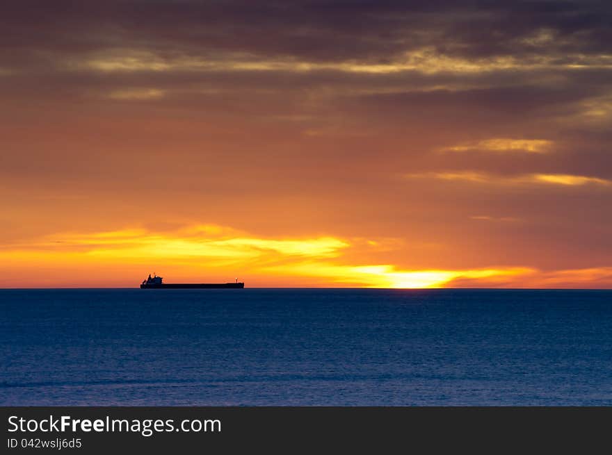 Cargo ship on horizon at dawn