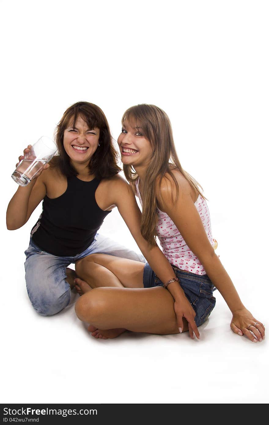 Two cheerful girls hold a glass with water