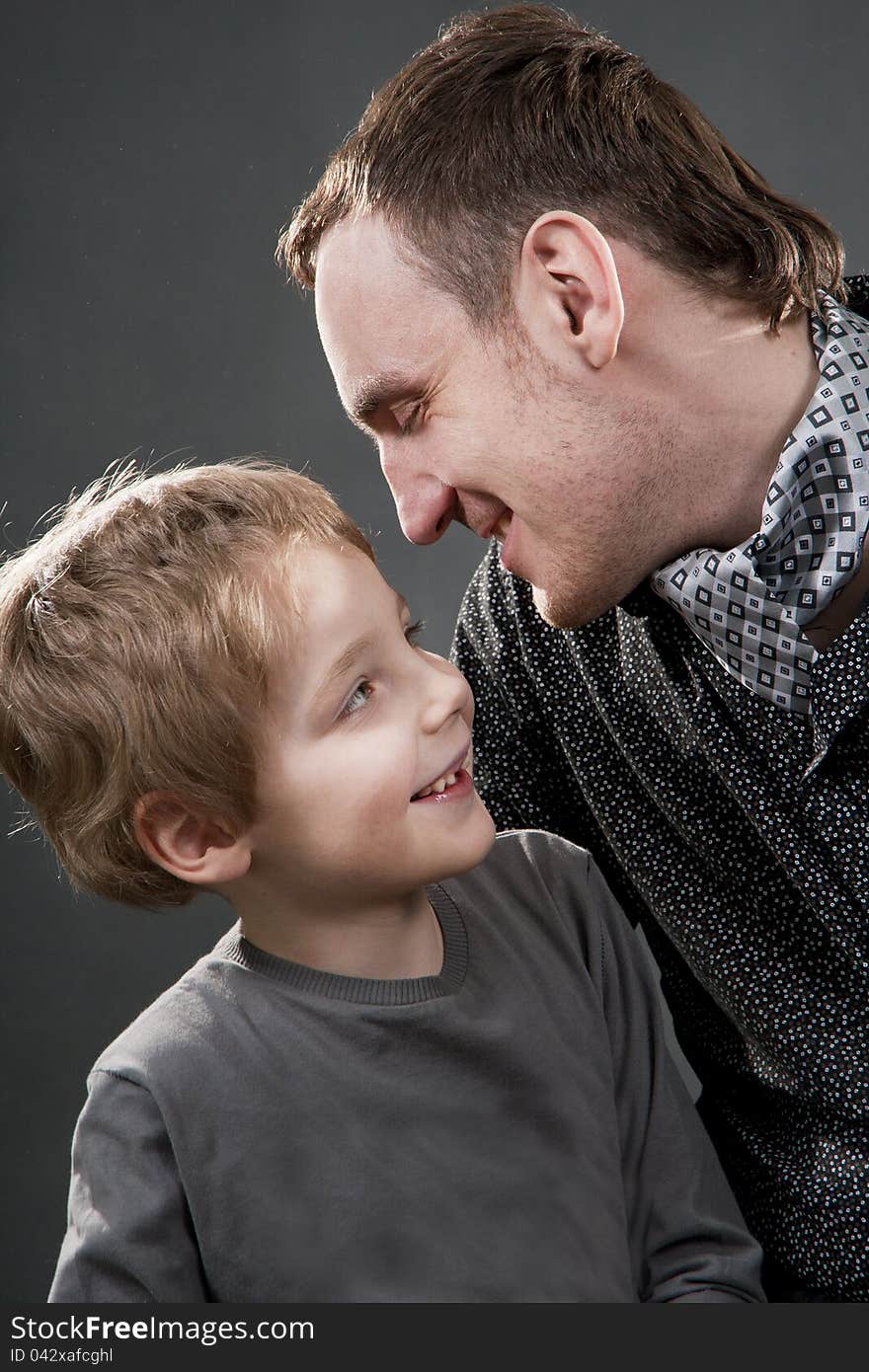 Father and son cheerfully talk. On a gray background.