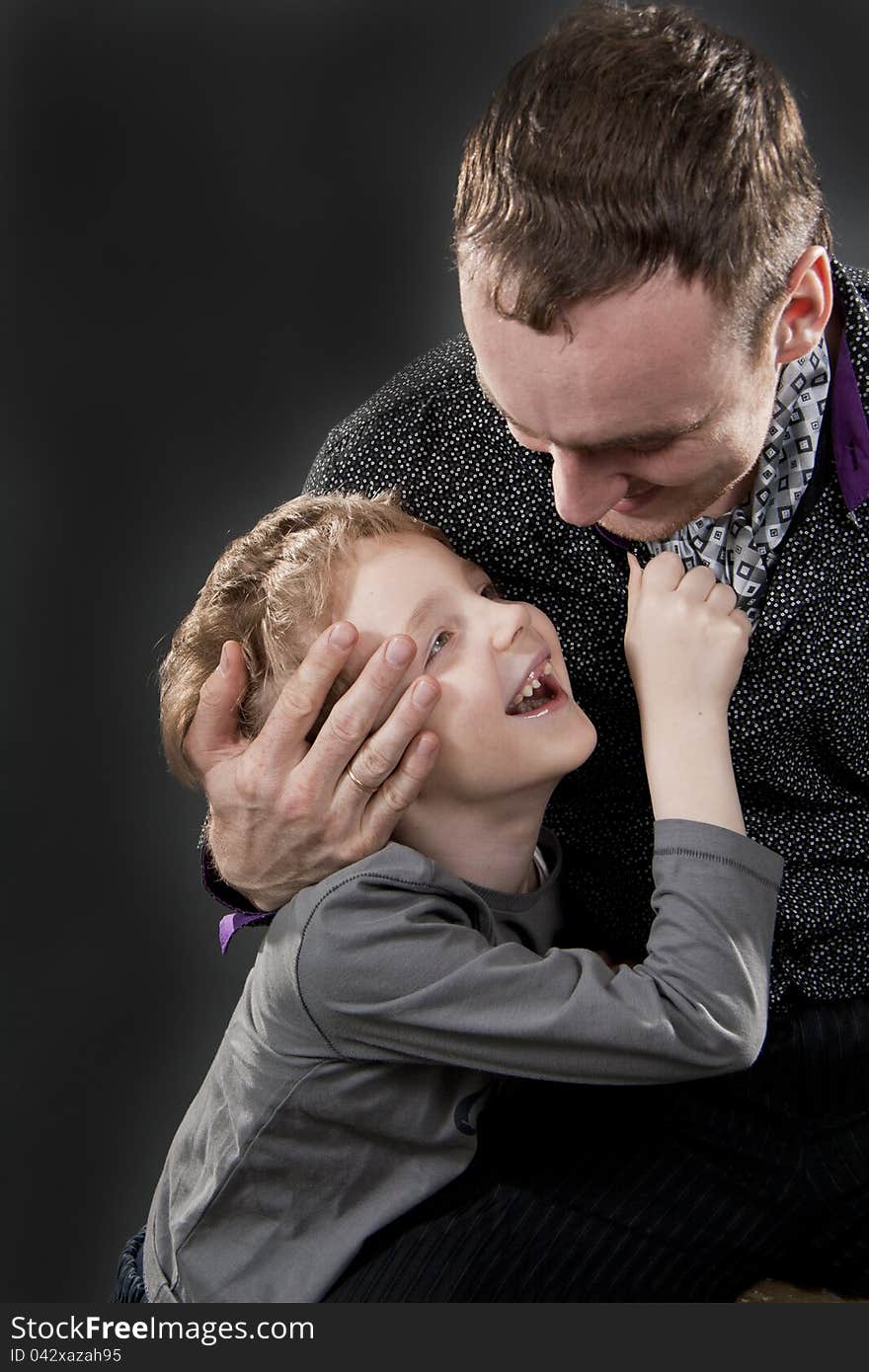 Father and son cheerfully talk. On a gray background. Boy not in focus.