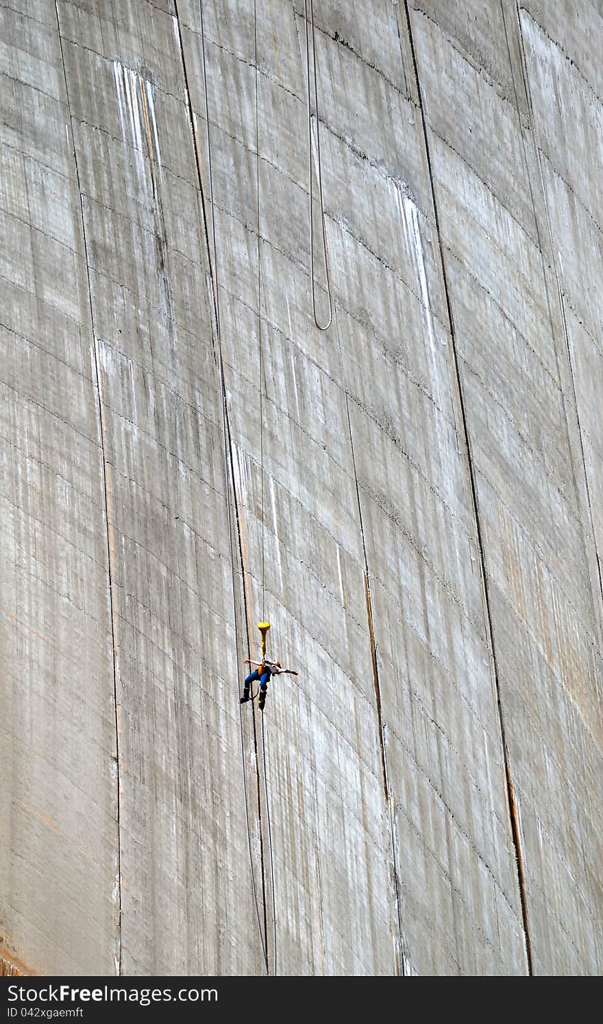 The woman is bungee jumping along the concrete wall. The Contra Dam is a popular bungee jumping venue in the Swiss Alps. The woman is bungee jumping along the concrete wall. The Contra Dam is a popular bungee jumping venue in the Swiss Alps.