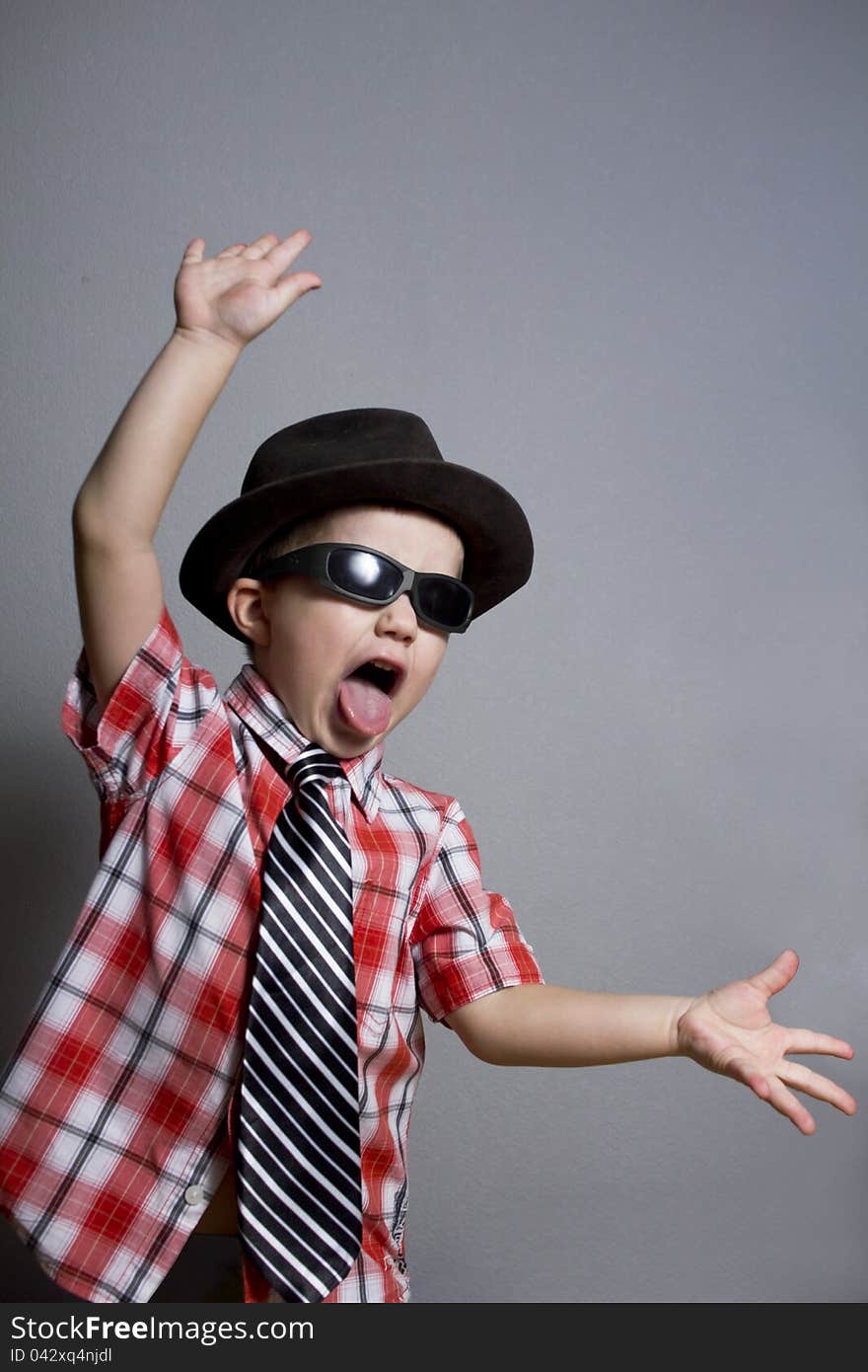 The boy in a hat and black glasses on a gray background