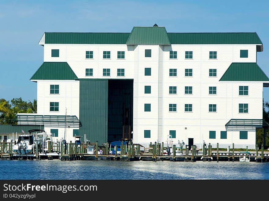 A large white boathouse with door open overlooks bay in florida. A large white boathouse with door open overlooks bay in florida.