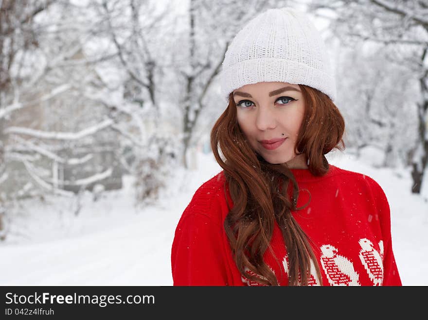 Portrait of beautiful young red hair woman outdoors in winter looking at camera and enjoying snow