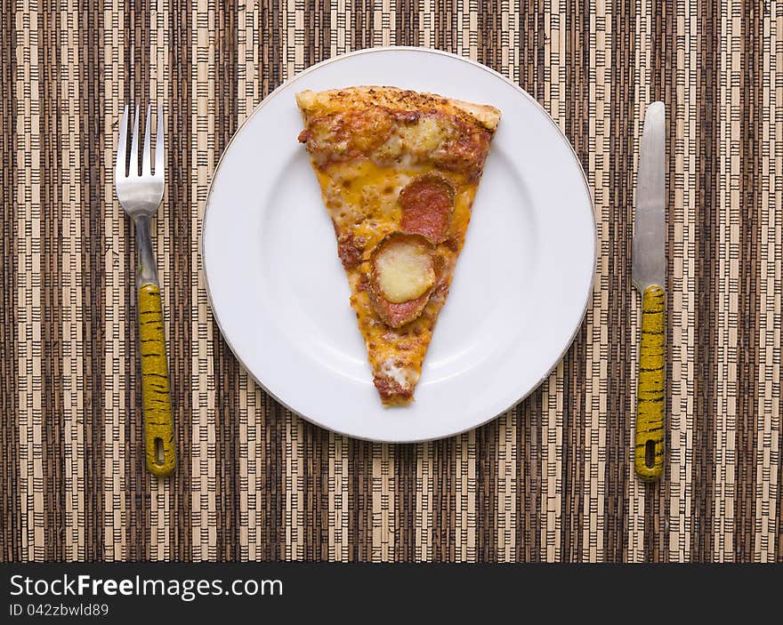 A slice of pizza on white plate with fork and knife, good for your articles