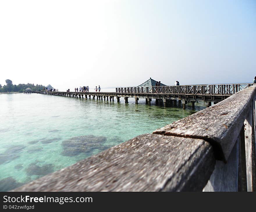 A little wooden bridge connecting two small islands over the sea. A little wooden bridge connecting two small islands over the sea