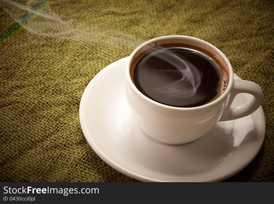 Cup with hot coffee on a green canvas