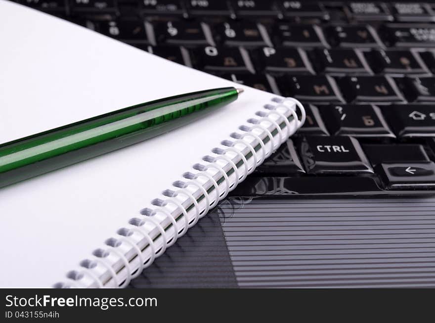 Concept of workplace, notebook and pen set on the background of a laptop. Concept of workplace, notebook and pen set on the background of a laptop