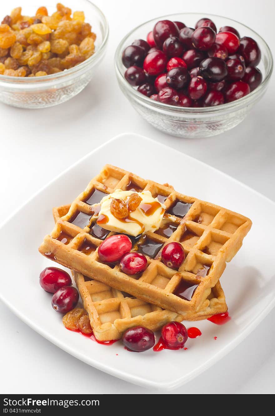 A plate of waffles with fresh fruits and honey