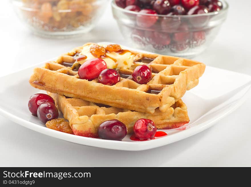 A plate of waffles with fresh fruits and honey