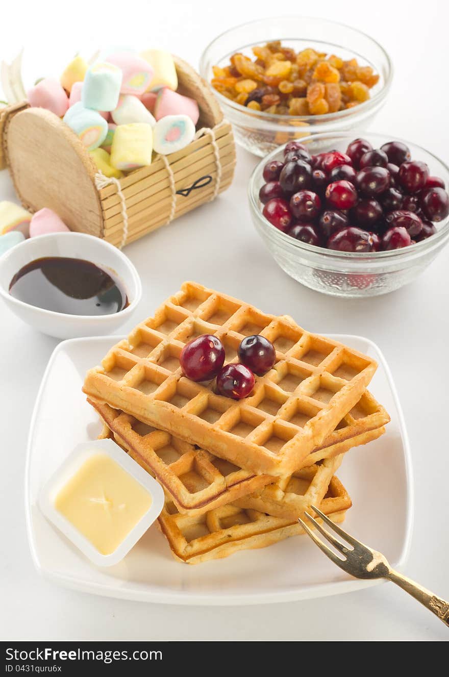 A plate of waffles with fresh fruits and butter