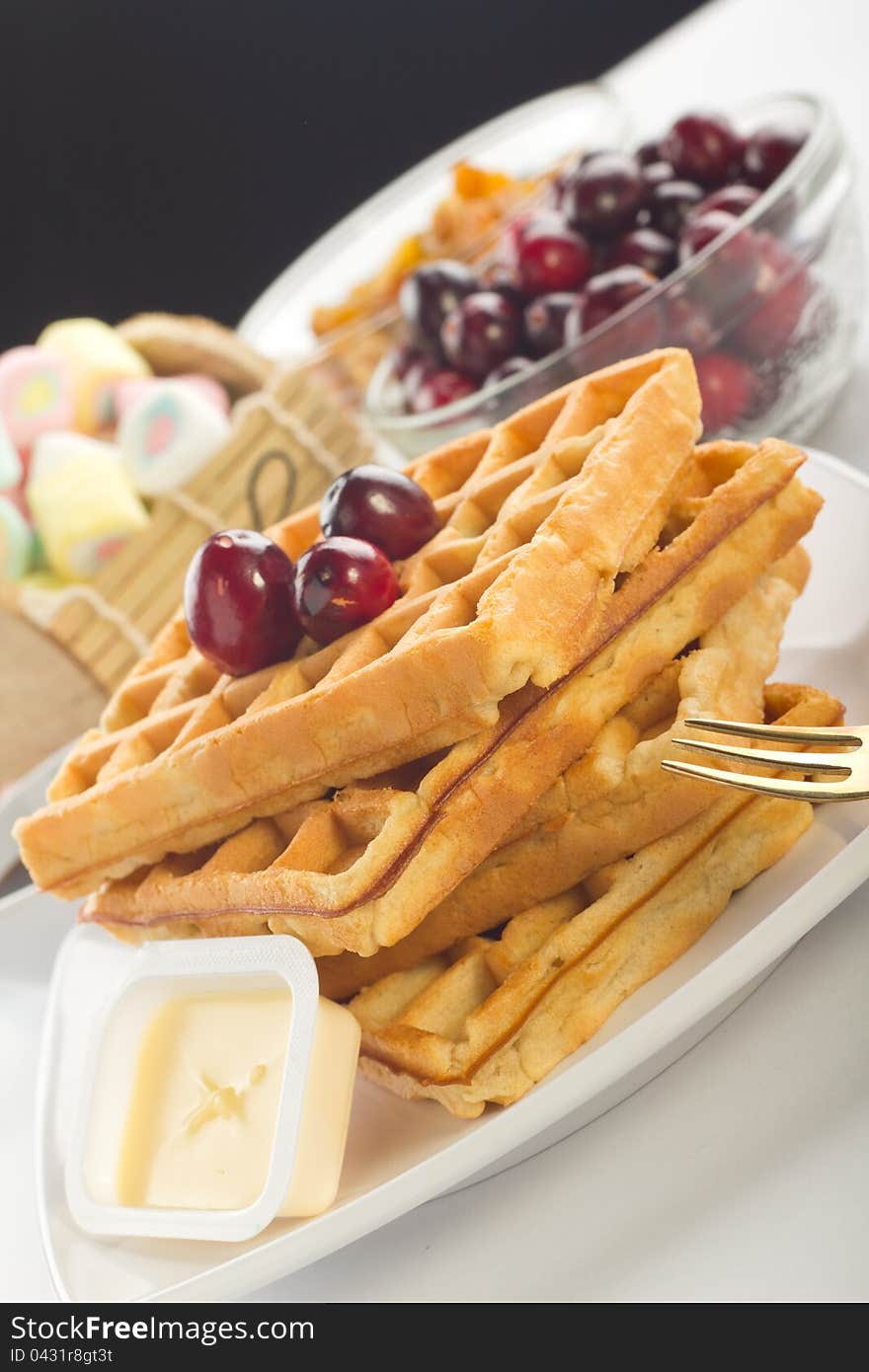 A plate of waffles with fresh fruits and butter