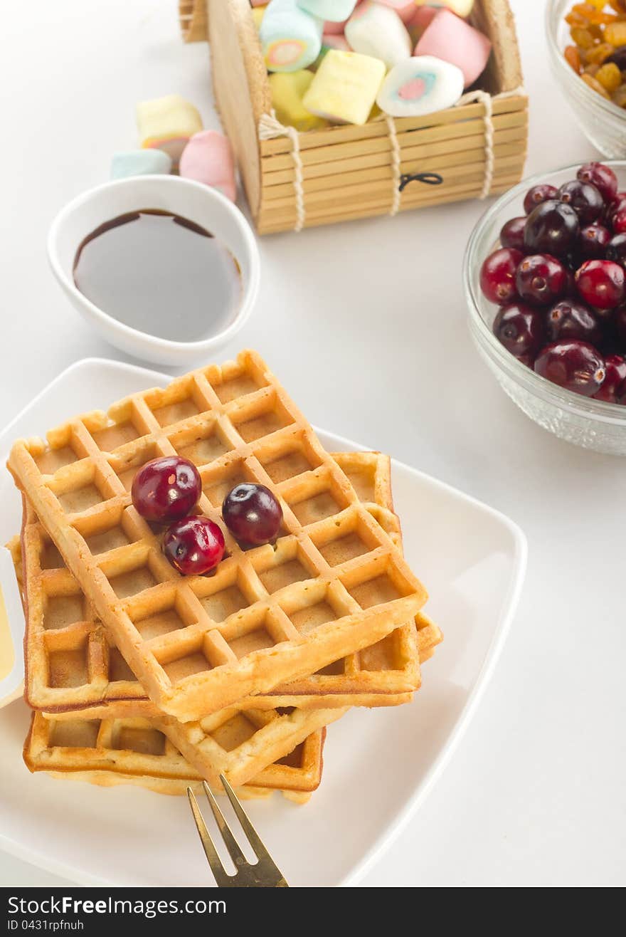 A plate of waffles with fresh fruits and butter