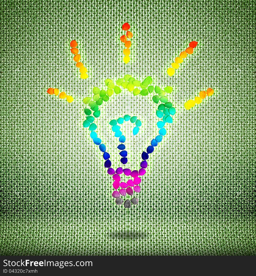 Idea template. Multi-colored light bulb from seeds on a green background