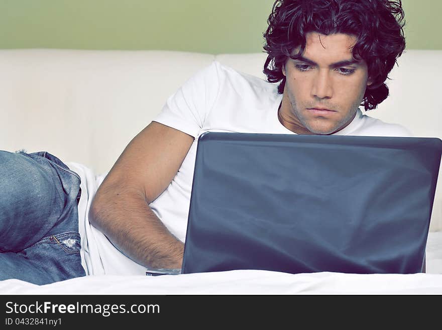 Attractive young man is working from bed with wireless laptop. Attractive young man is working from bed with wireless laptop