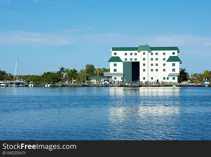 A large white boathouse with door open overlooks bay in florida. A large white boathouse with door open overlooks bay in florida.