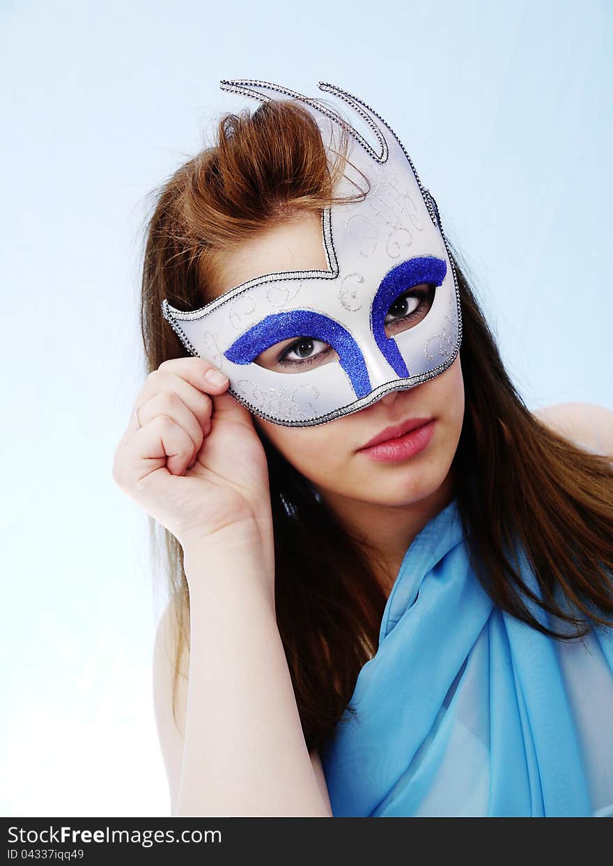 Masquerade Mask on pretty brunette. Soft Blue costume and background. Masquerade Mask on pretty brunette. Soft Blue costume and background