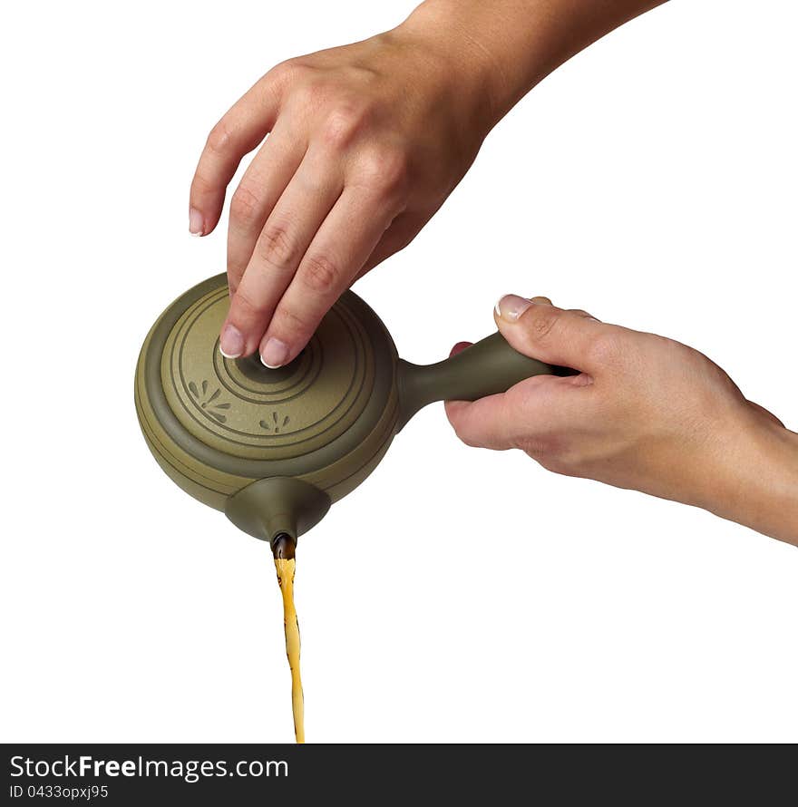 Tea being poured into glass tea cup isolated on a white background.