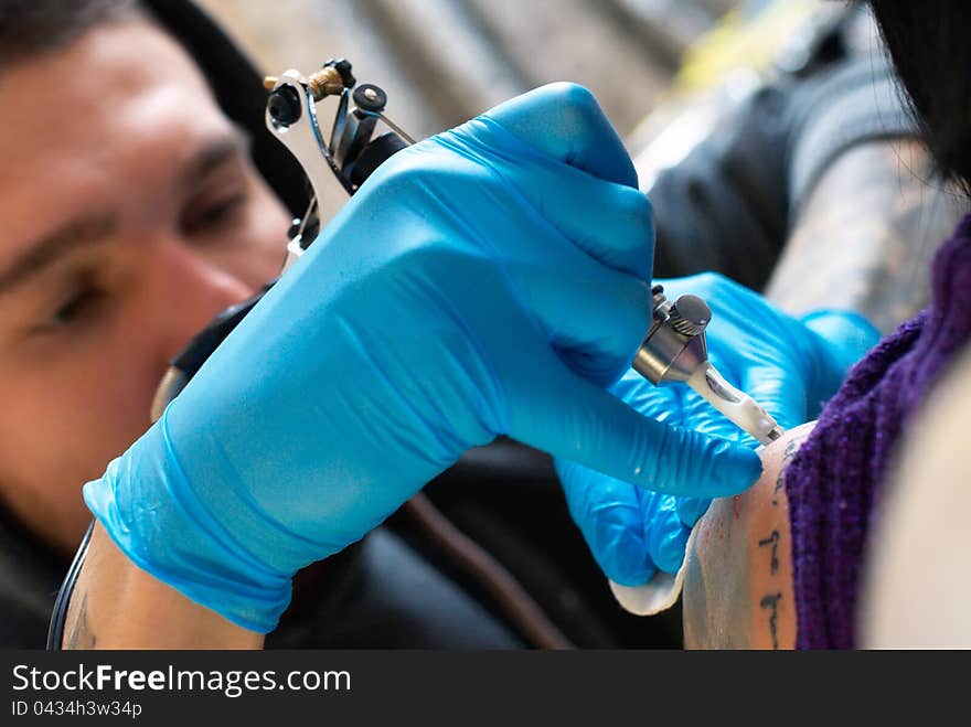 Bearded Caucasian tattooist creates a tattoo on a woman's shoulder, close up