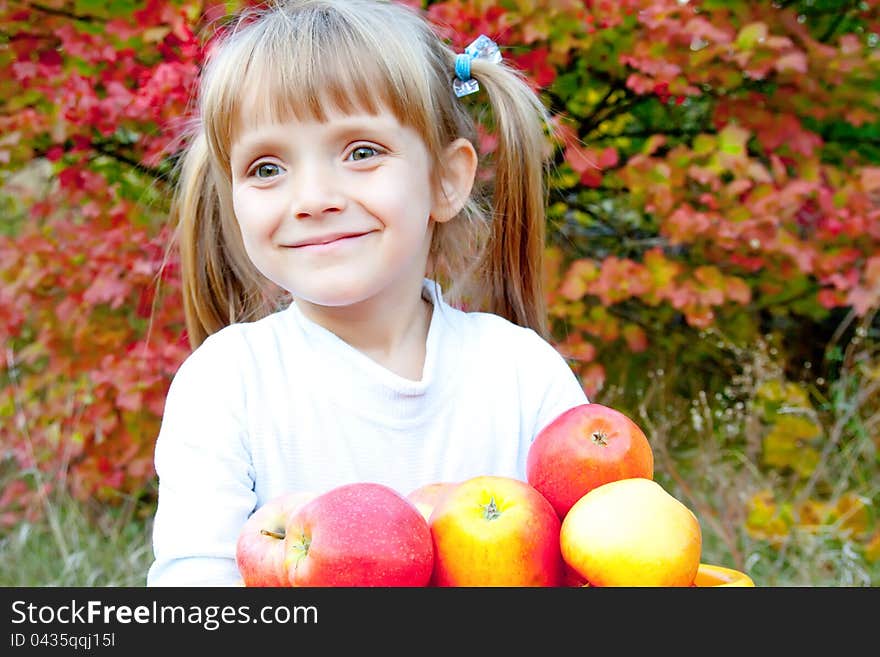 Little girl with fresh vegetables in garden