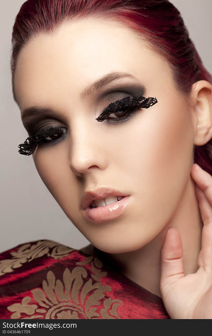 Closeup shot of red-headed model with long eye-lashes and red fabric over shoulder. Closeup shot of red-headed model with long eye-lashes and red fabric over shoulder