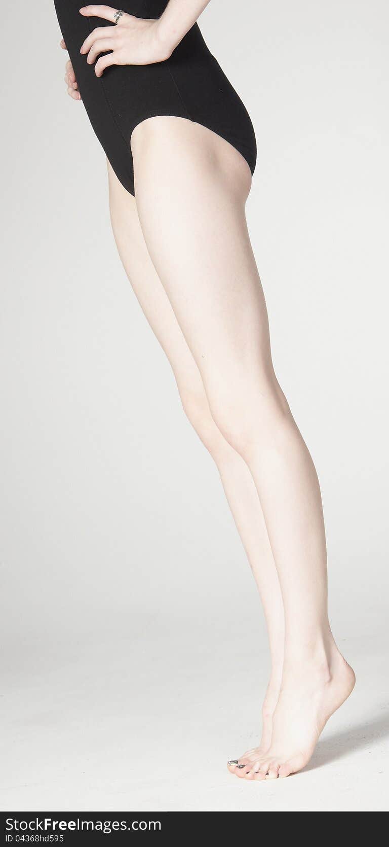 Side View Close Up of Woman's Bare Legs Standing Wearing Black Leotard Isolated Against a White Background. Side View Close Up of Woman's Bare Legs Standing Wearing Black Leotard Isolated Against a White Background