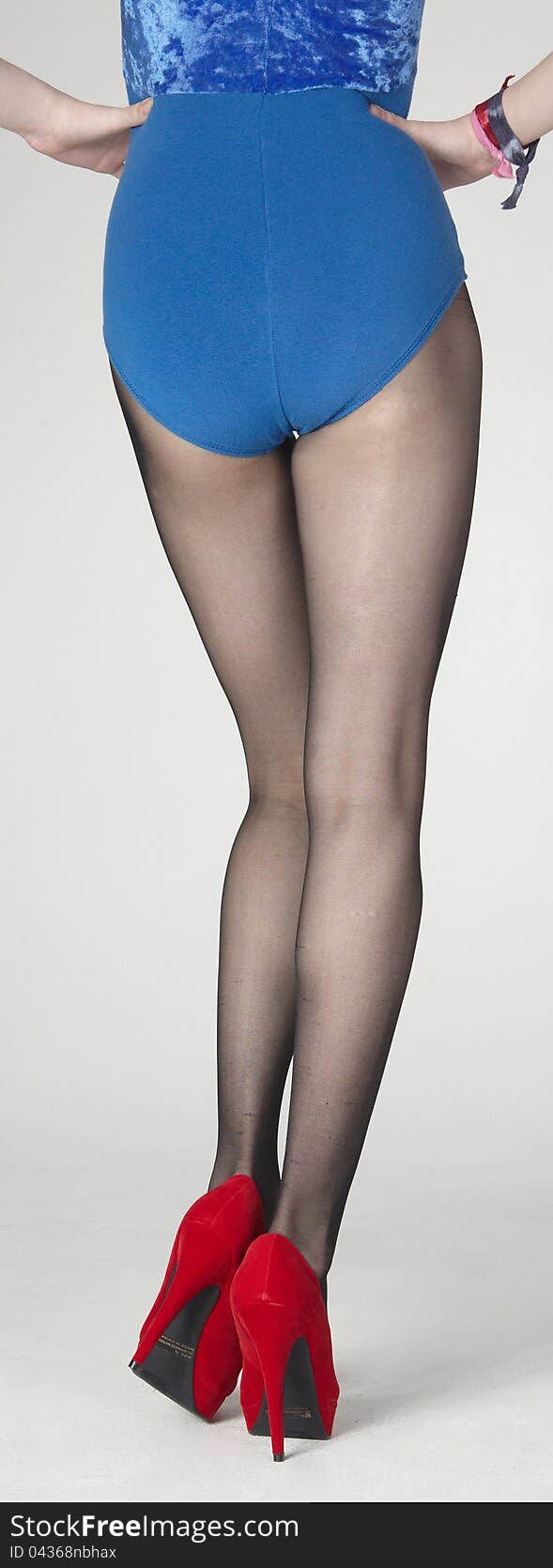 Rear View Close Up of Woman's Legs Wearing Dark Pantyhose, Red Heels and a Blue Leotard Isolated Against a White Background. Rear View Close Up of Woman's Legs Wearing Dark Pantyhose, Red Heels and a Blue Leotard Isolated Against a White Background