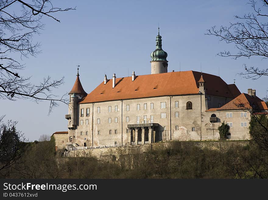 Renaissance castle, lock in the new town of metují, castle in the background with a blue sky, castle in the sunlight, lock with an orange roof