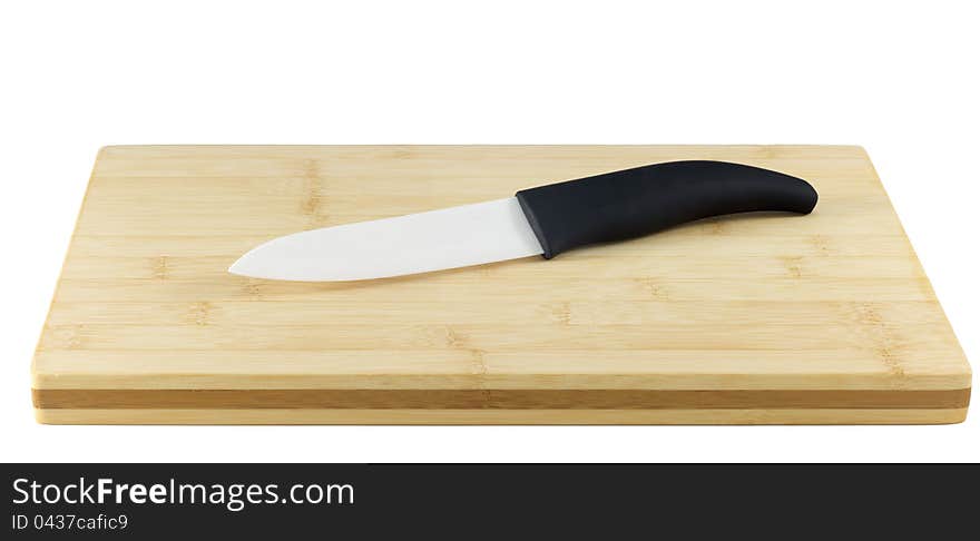 Ceramic Knife on a chopping board isolated on white. Ceramic knives will not corrode in harsh environments, are non-magnetic, and do not conduct electricity. Their resistance to strong acid and caustic substances, and their ability to retain a cutting edge longer than forged metal knives, make them a suitable culinary tool for slicing boneless meat, vegetables and fruit.